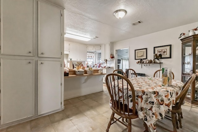 dining area featuring visible vents and a textured ceiling