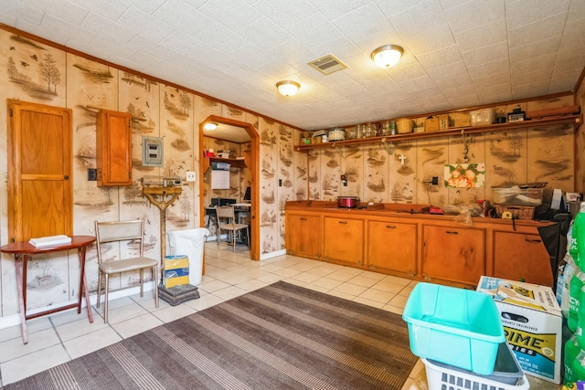 kitchen featuring arched walkways, brown cabinetry, light tile patterned flooring, and visible vents