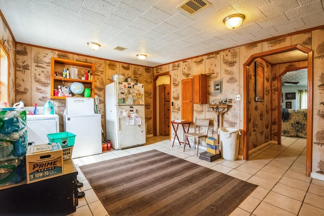 kitchen featuring arched walkways, washing machine and dryer, visible vents, ornamental molding, and freestanding refrigerator