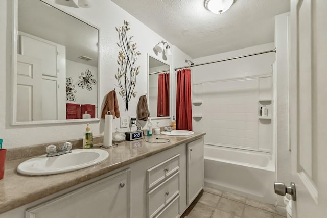 bathroom featuring a textured ceiling, double vanity, a sink, and tile patterned floors