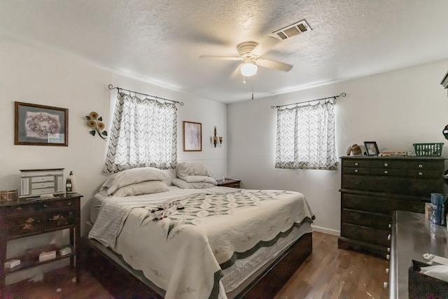 bedroom with baseboards, visible vents, ceiling fan, wood finished floors, and a textured ceiling