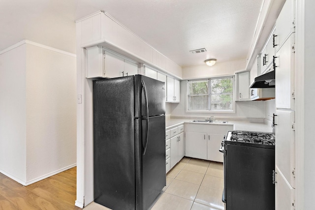 3230 Virginia St, La Marque, TX 77568 - kitchen featuring visible vents, under cabinet range hood, light countertops, black appliances, and a sink