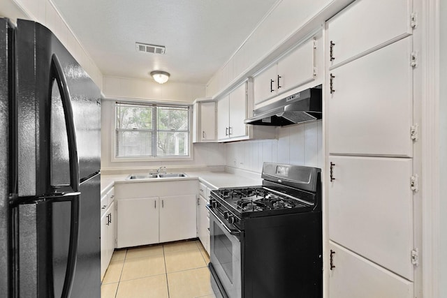 3230 Virginia St, La Marque, TX 77568 - kitchen featuring light tile patterned flooring, under cabinet range hood, visible vents, stainless steel range with gas cooktop, and freestanding refrigerator