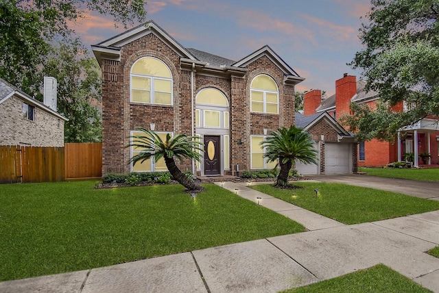 traditional home featuring brick siding, driveway, a front lawn, and fence