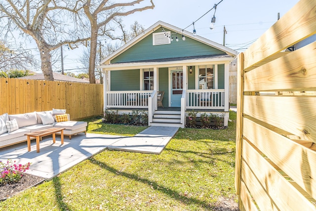 view of front of home with covered porch, fence, an outdoor living space, a patio area, and a front lawn