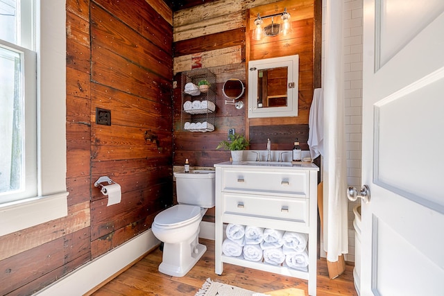 bathroom with vanity, wooden walls, toilet, and wood finished floors