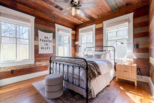 bedroom with wooden ceiling, wood walls, and hardwood / wood-style floors