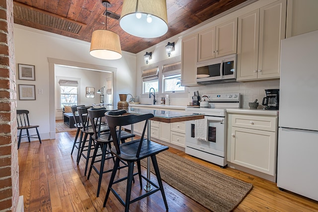 kitchen with wooden ceiling, white appliances, and a healthy amount of sunlight