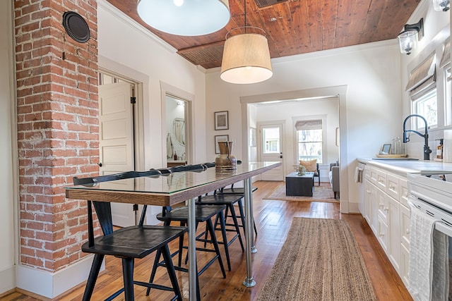 dining space featuring wooden ceiling, light wood-style flooring, baseboards, and crown molding