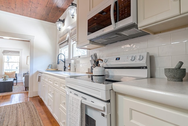 kitchen with white appliances, a sink, a healthy amount of sunlight, light countertops, and decorative backsplash