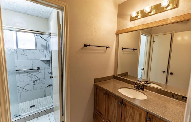 full bathroom with a stall shower, a textured ceiling, and vanity