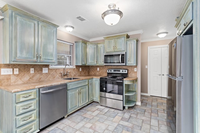 kitchen featuring visible vents, decorative backsplash, appliances with stainless steel finishes, ornamental molding, and a sink