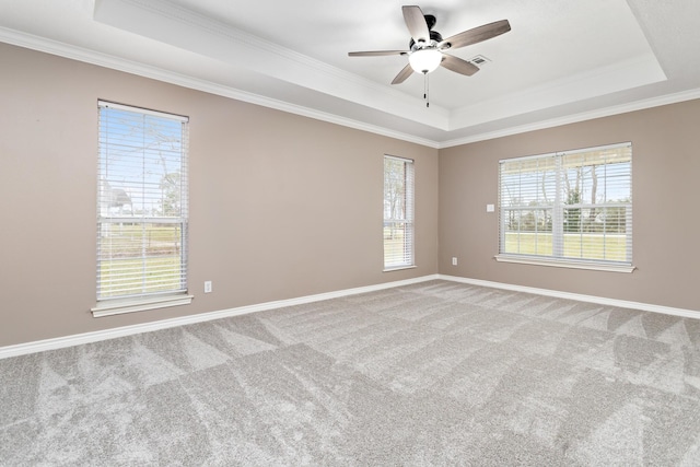 carpeted empty room with baseboards, a tray ceiling, a ceiling fan, and ornamental molding