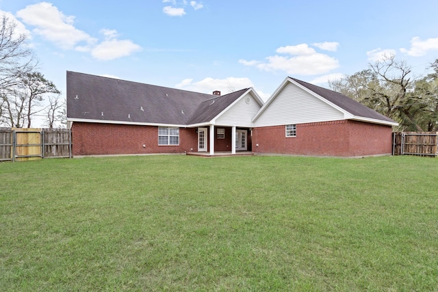 back of property featuring a fenced backyard, a lawn, and brick siding