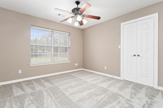 carpeted empty room with baseboards, visible vents, and a ceiling fan