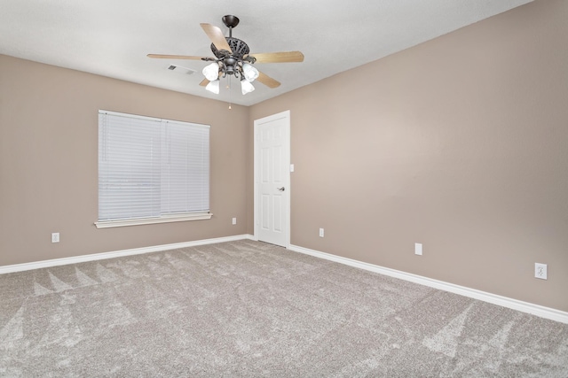 empty room with carpet floors, visible vents, baseboards, and a ceiling fan