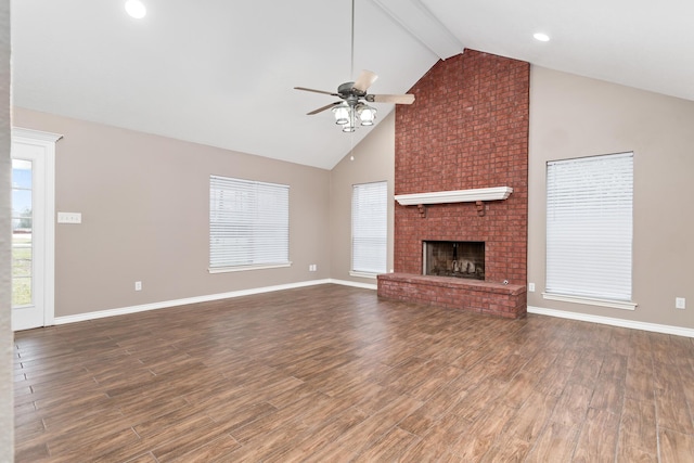 unfurnished living room featuring a wealth of natural light, a fireplace, beam ceiling, and wood finished floors