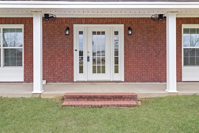 entrance to property featuring a porch and brick siding