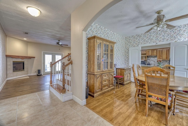 dining area featuring arched walkways, wallpapered walls, light wood-style floors, and baseboards