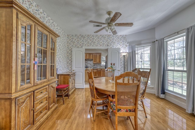 dining room featuring wallpapered walls, light wood-style floors, visible vents, and baseboards