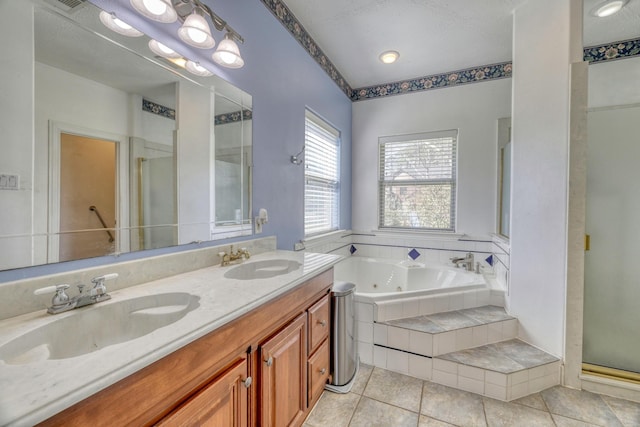 bathroom with double vanity, a tub with jets, a stall shower, and a sink