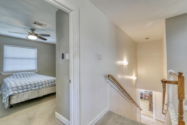 stairs featuring visible vents, baseboards, carpet, and a ceiling fan