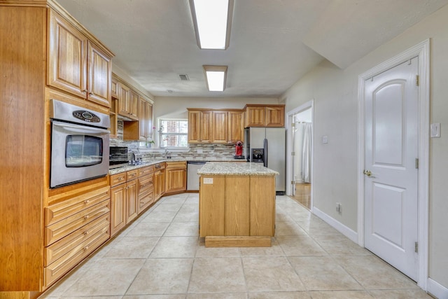 kitchen featuring visible vents, a kitchen island, light tile patterned floors, decorative backsplash, and stainless steel appliances