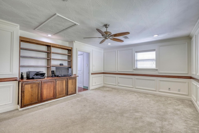 unfurnished office featuring light carpet, a decorative wall, visible vents, and ornamental molding