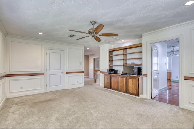 interior space featuring carpet, white cabinets, a ceiling fan, and a decorative wall