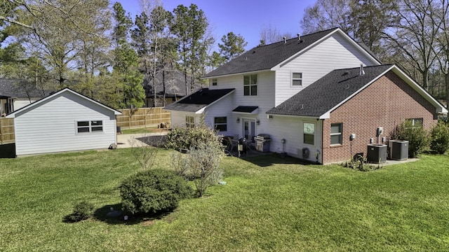 rear view of house featuring brick siding, cooling unit, a yard, and fence