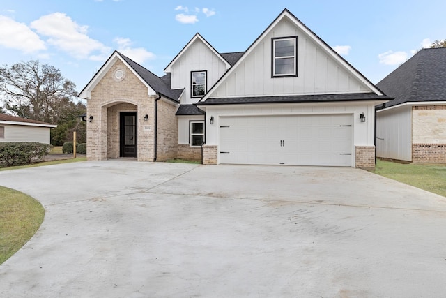 view of front of house with a garage, driveway, brick siding, and board and batten siding