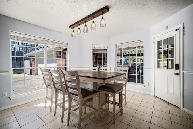 dining space featuring tile patterned flooring, a textured ceiling, and baseboards