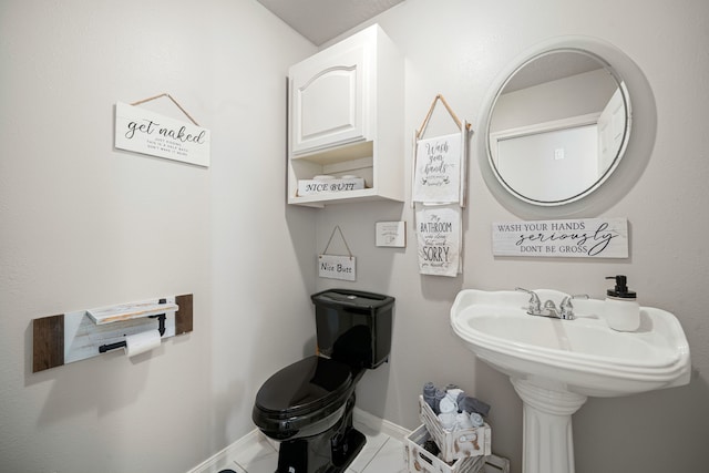 half bath featuring tile patterned flooring, toilet, and baseboards