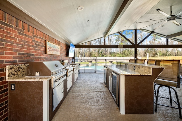 view of patio / terrace with outdoor wet bar, area for grilling, a sink, fence, and exterior kitchen