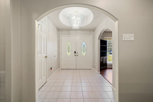 entrance foyer with baseboards, a notable chandelier, and light tile patterned flooring