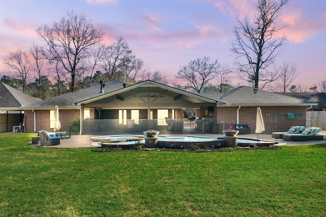 rear view of house with a patio, a lawn, fence, and a hot tub