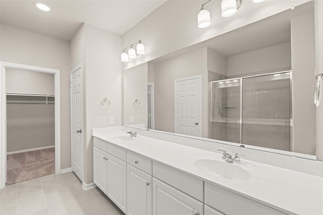 full bathroom with double vanity, a stall shower, a sink, and tile patterned floors