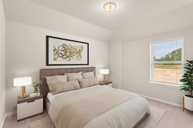 bedroom featuring lofted ceiling, light carpet, and baseboards