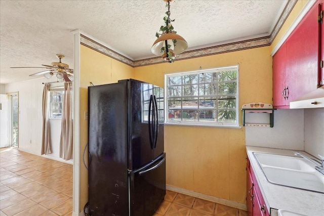 kitchen with a textured ceiling, ceiling fan, a sink, light countertops, and freestanding refrigerator