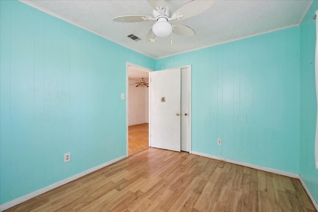 unfurnished bedroom featuring ceiling fan, ornamental molding, wood finished floors, and visible vents