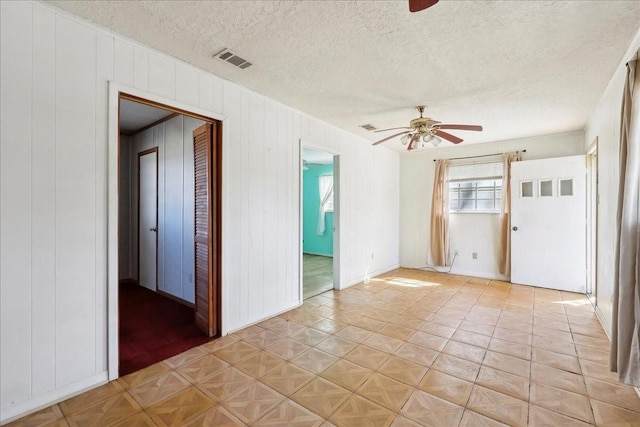 empty room featuring a textured ceiling, visible vents, and a ceiling fan