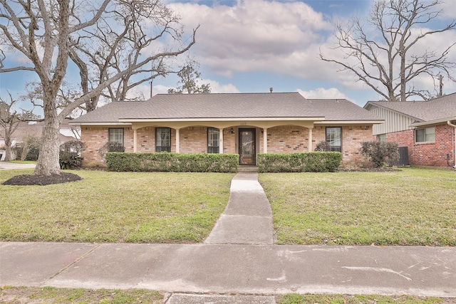 view of front of home featuring a shingled roof, a front yard, cooling unit, and brick siding