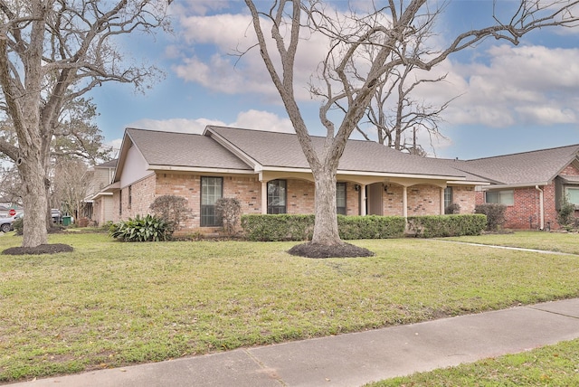 ranch-style house featuring brick siding, roof with shingles, and a front yard