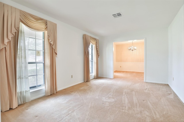 carpeted empty room featuring baseboards, visible vents, and an inviting chandelier