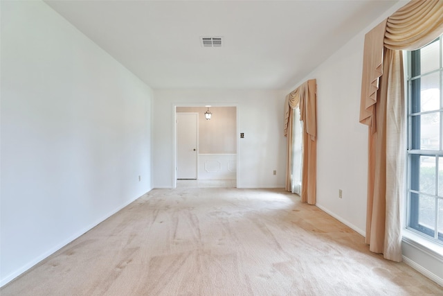 empty room featuring plenty of natural light, visible vents, and light colored carpet