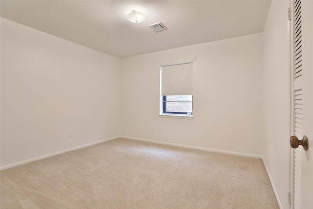 spare room featuring light carpet, visible vents, and baseboards