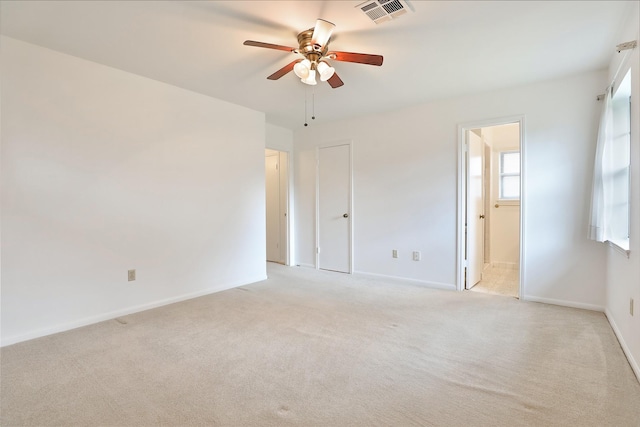 empty room featuring light carpet, ceiling fan, visible vents, and baseboards