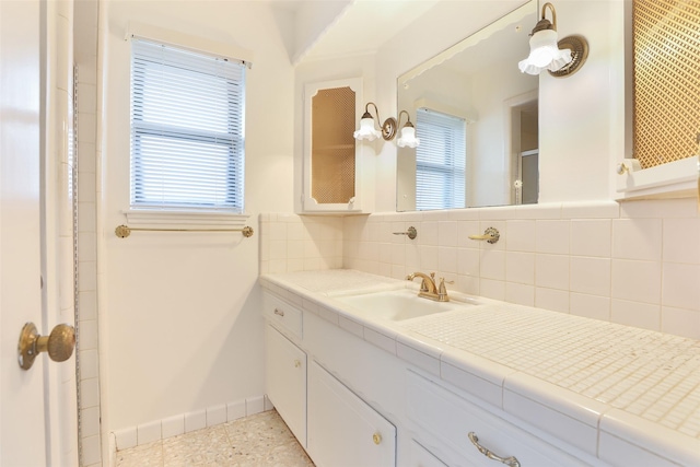 bathroom featuring walk in shower, backsplash, vanity, and baseboards