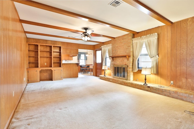 unfurnished living room with wooden walls, visible vents, beamed ceiling, and carpet flooring