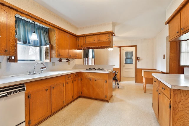 kitchen featuring a peninsula, white appliances, a sink, brown cabinets, and light floors